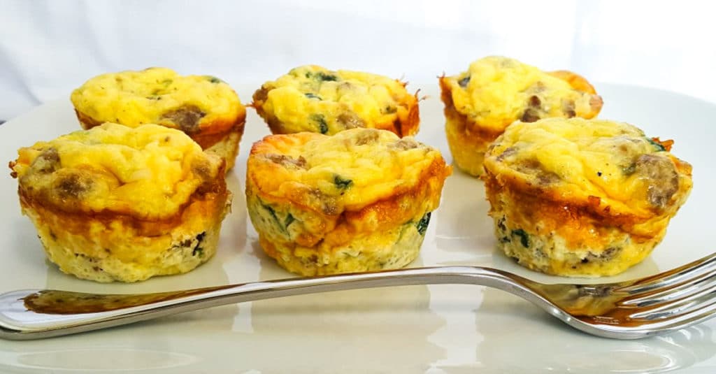 Make Ahead Sausage Egg cups sitting on a white plate with a fork in front