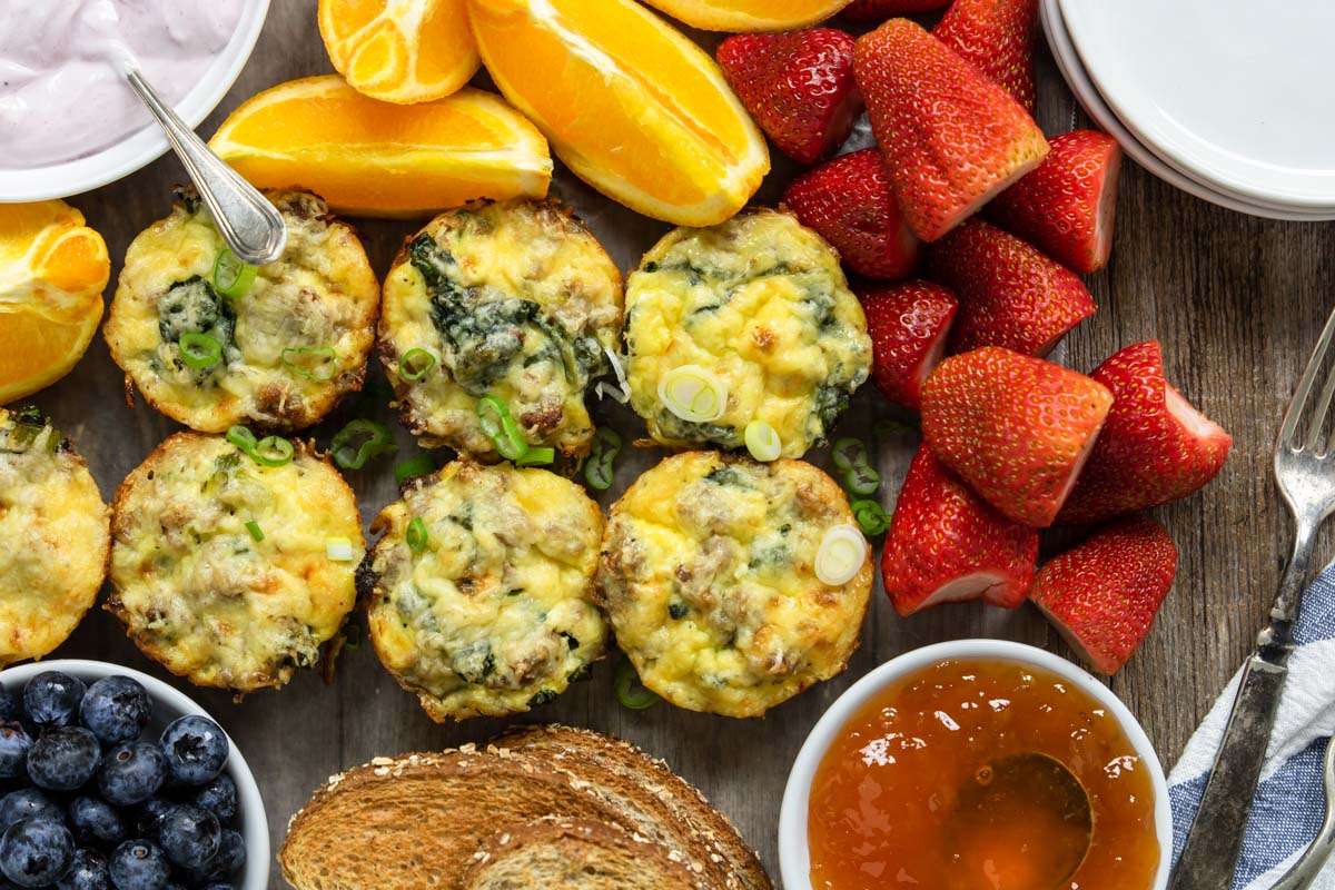 egg cups, fruit, yogurt and toast on a breakfast board