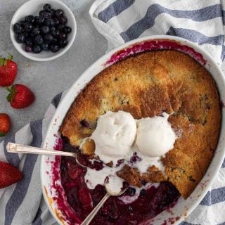 Berry cobbler with vanilla cake like topping and topped with two scoops of vanilla ice cream