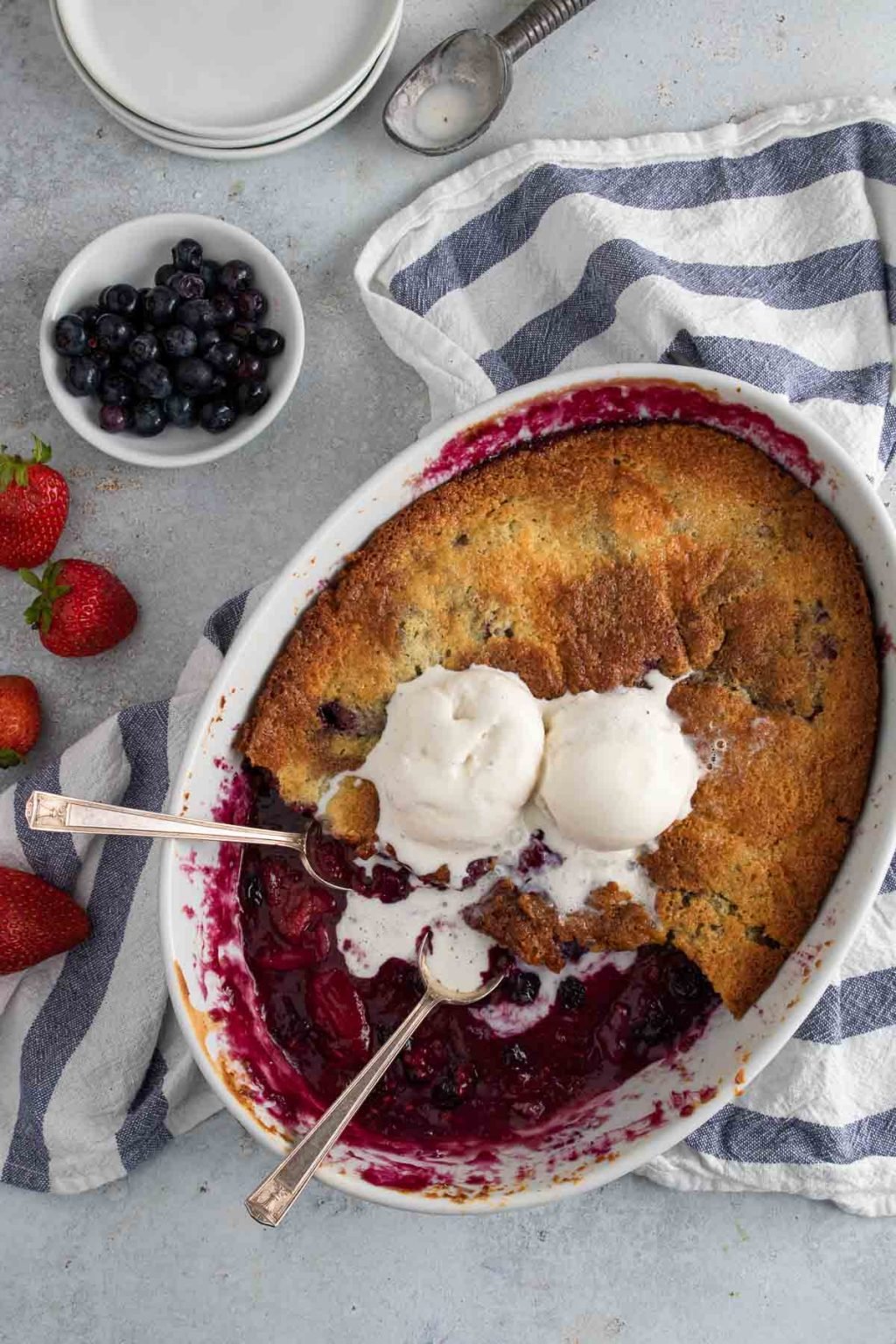 Berry cobbler with vanilla cake like topping and topped with two scoops of vanilla ice cream