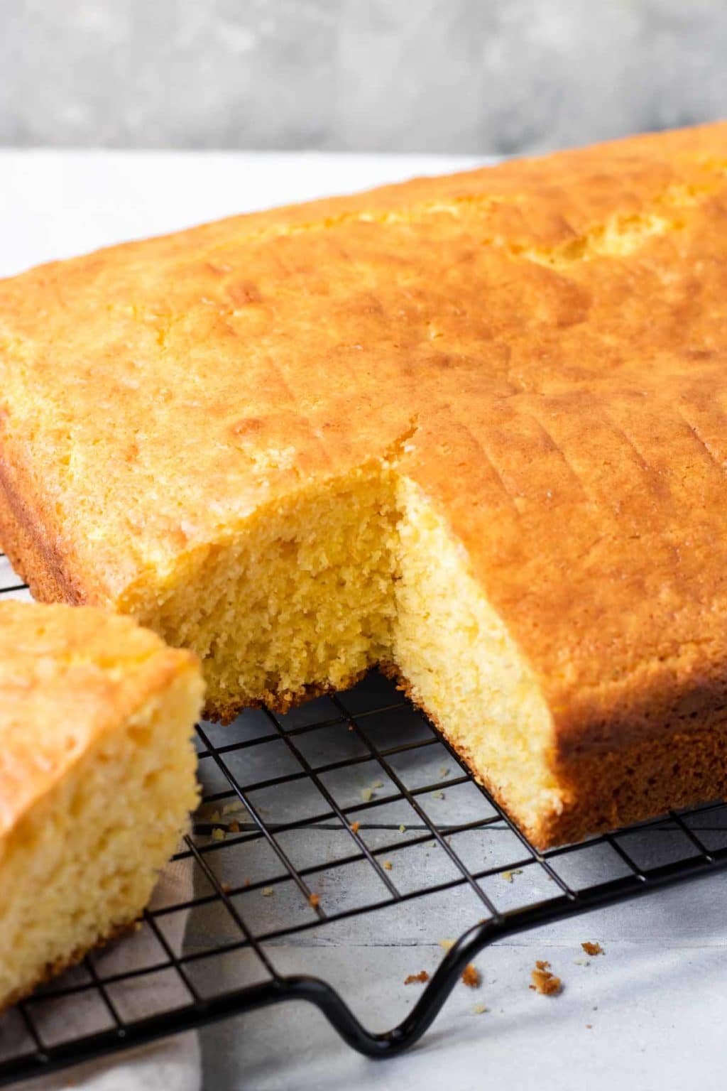 Cornbread made with a box of yellow cake mix and two jiffy corn muffin mixes, cooling on a black cooling rack