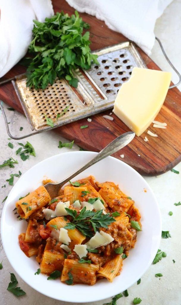 Instant Pot Sausage Rigatoni with tomato cream sauce in a bowl with parsley and parmesan