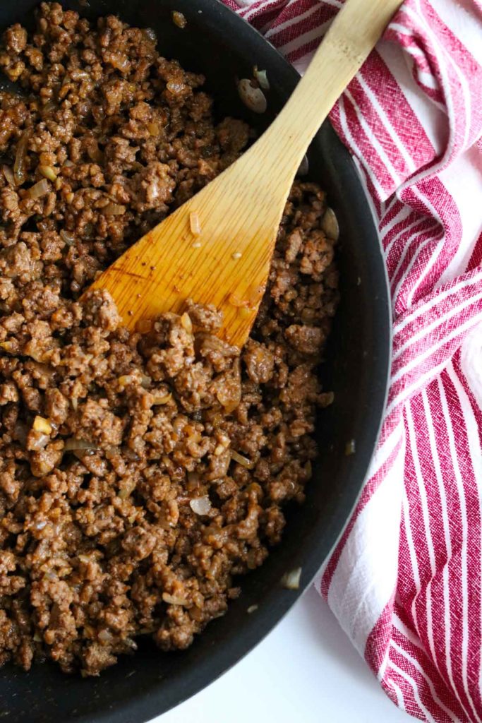 Homemade Sloppy Joe ground beef mixture in a skillet with a spatula and a napkin to the side
