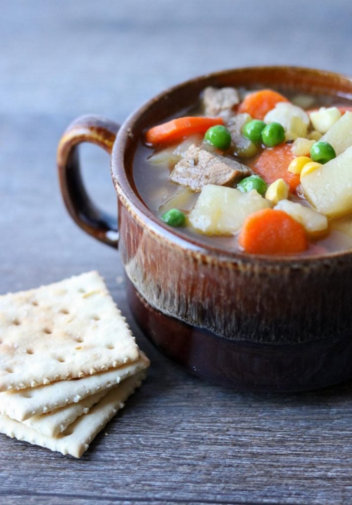 Instant Pot Steak Soup in a brown mug with a stack of saltine crackers to the side