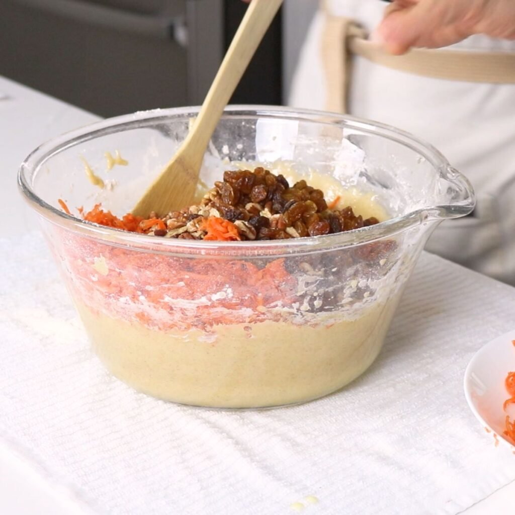 stirring in carrots, pineapple, raisins, and pecans into batter