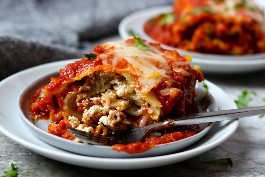 A lasagna roll up with a bite taken out of it showing all the layers and filling www.momsdinner.net