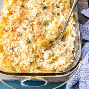 cheesy potatoes being served out of a casserole dish