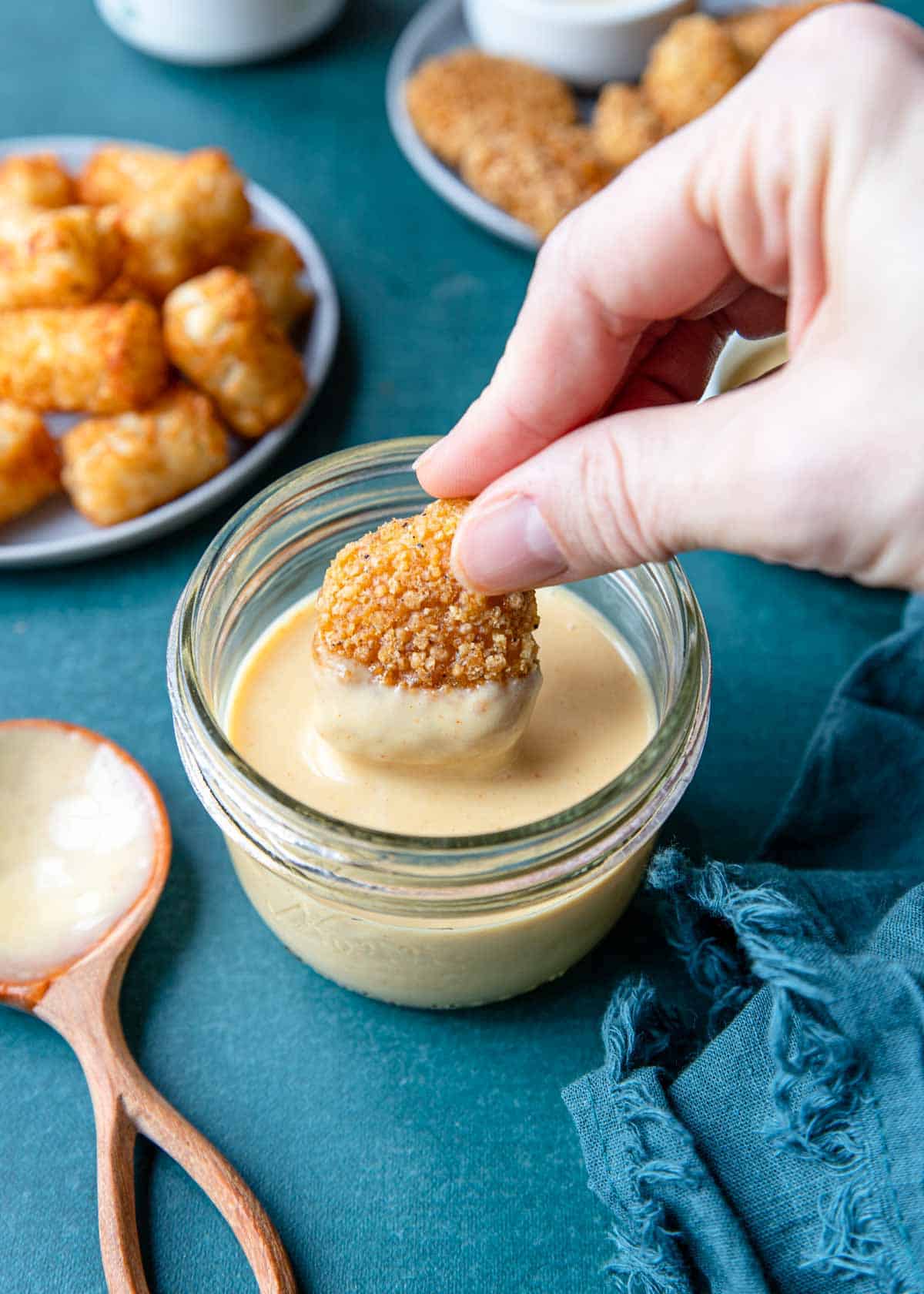 a crispy chicken nugget being dipped in honey mustard sauce