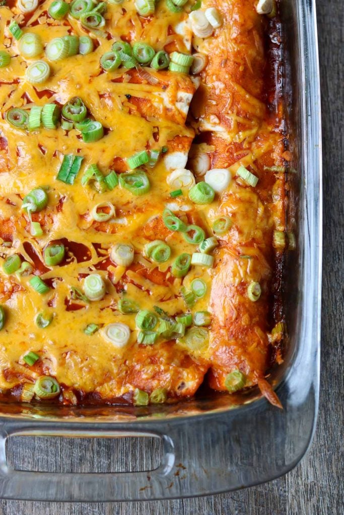 9x13 glass baking dish with chicken enchiladas garnished with green onions momsdinner.net