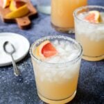 a glass of grapefruit margarita with a salty rim and a fresh grapefruit wedge