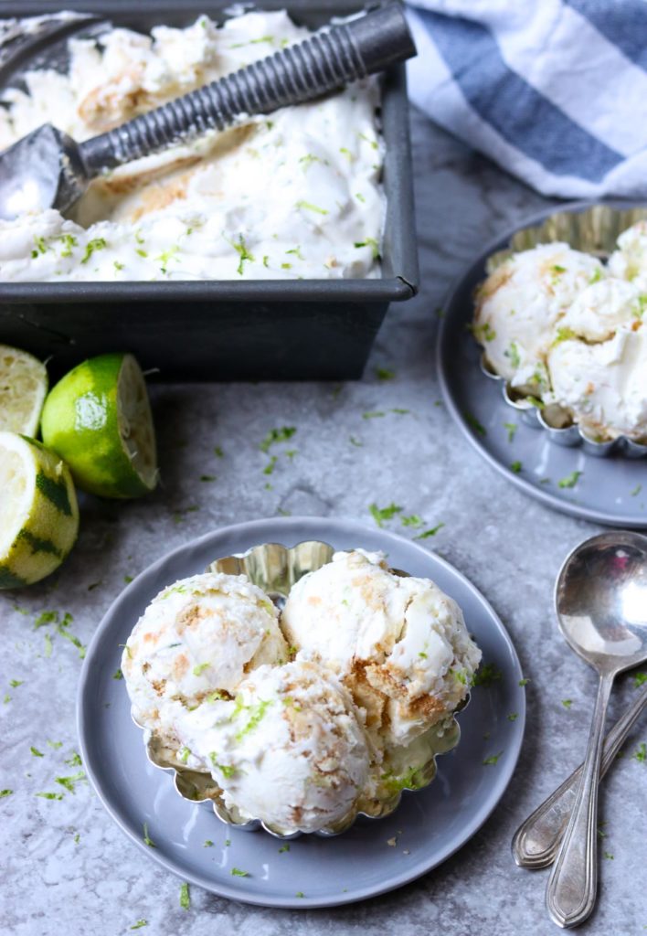 key lime ice cream with cookies mixed in sitting on a grey plate with spoons and limes to the side