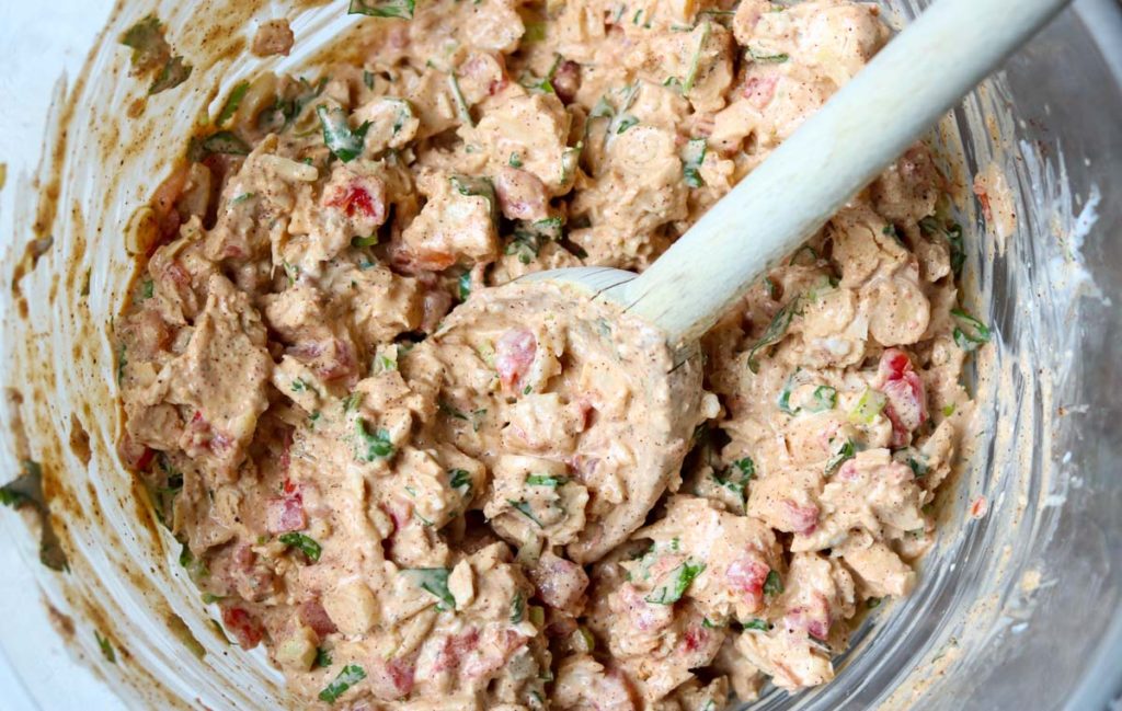Creamy Chicken Taco mixture in a glass mixing bowl with a wooden spoon