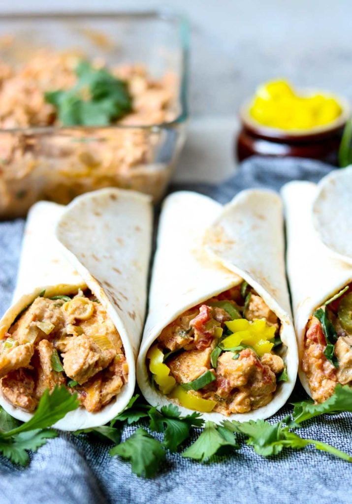 three chicken tacos in flour tortillas garnished with pepperoncinis and cilantro