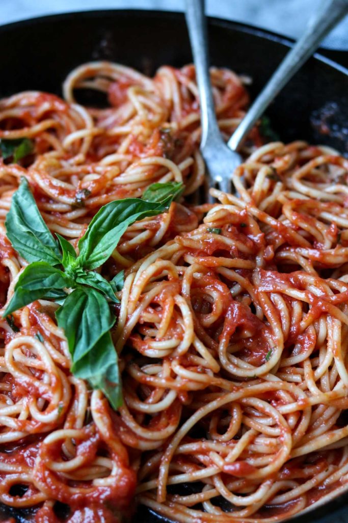 Easy Homemade Marinara Sauce with spaghetti in a pan with two forks, garnished with basil
