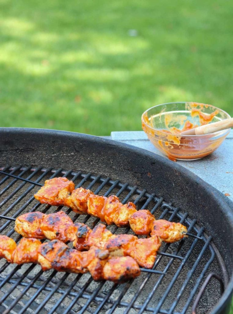 a grill with chicken skewers and bbq sauce