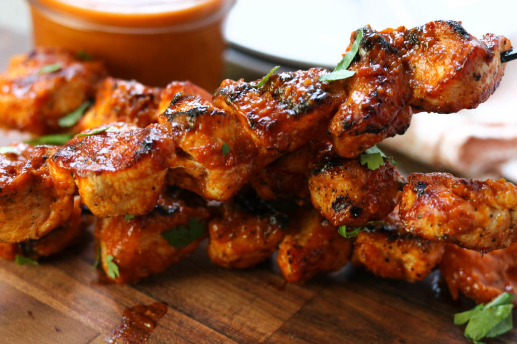 a close up of grilled chicken skewers