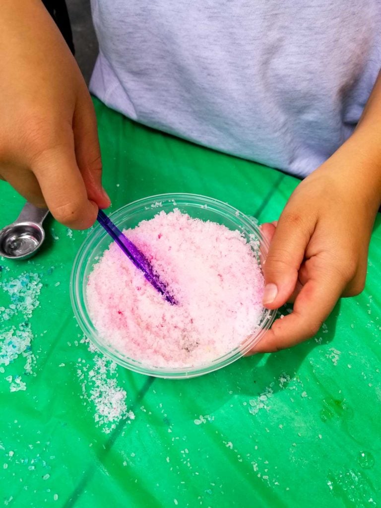 salts in a bowl being stirred with a purple spoon