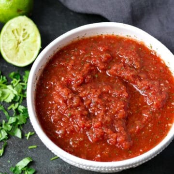 homemade salsa in a bowl with cilantro and limes
