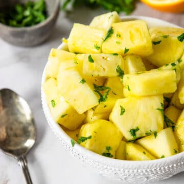 fresh pineapple in a bowl with a citrus cilantro glaze over top