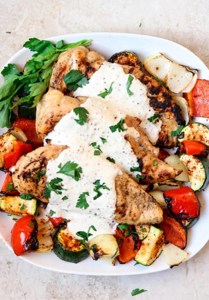 Grilled chicken over vegetables with a cream sauce poured over top