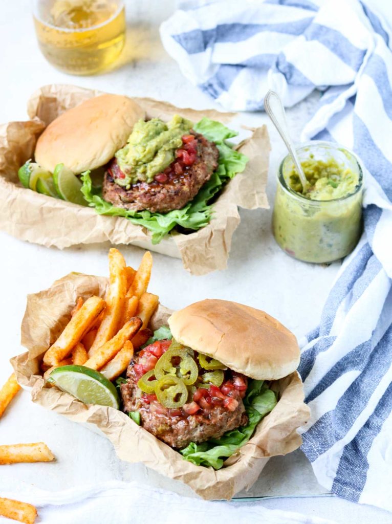 two turkey burgers topped with guacamole salsa and jalapenos