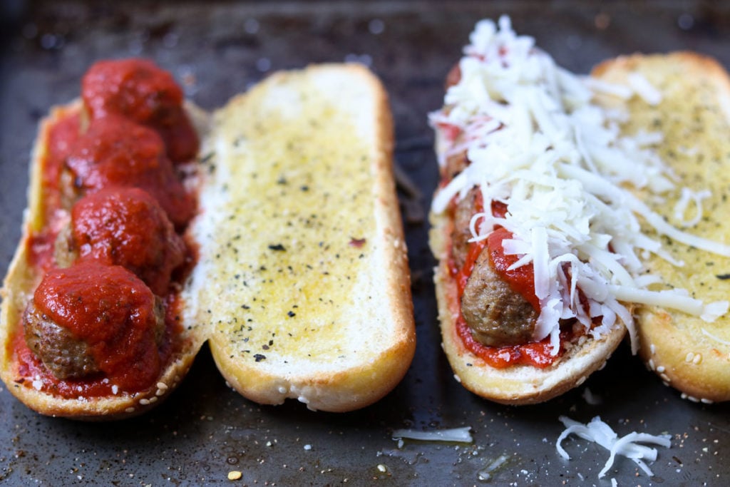 Two meatball sub sandwiches, one with cheese, one without 