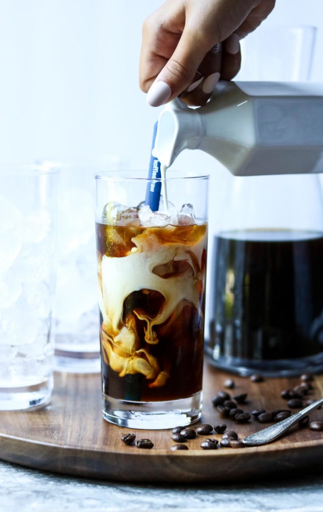 pouring cream into iced coffee