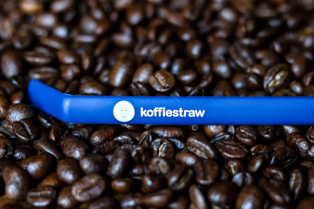 a plate of coffee beans with a blue koffiestraw