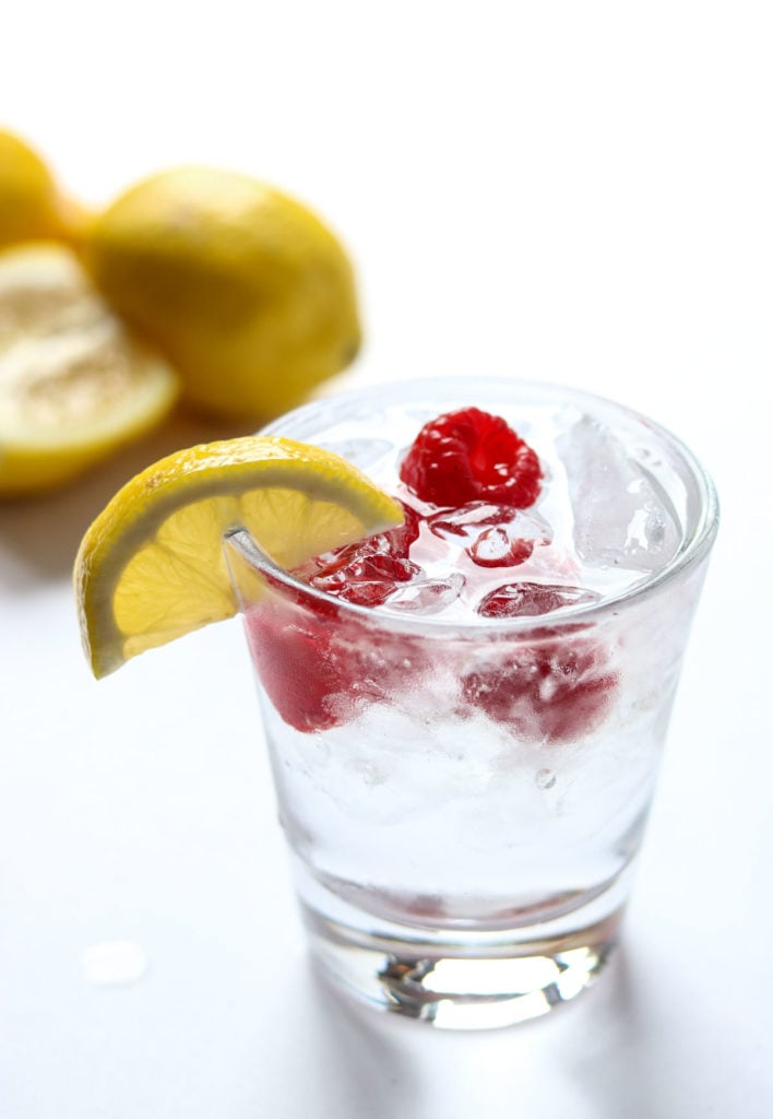 top of a cocktail that is garnished with lemon and raspberries