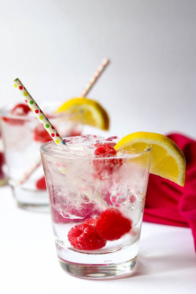 two raspberry vodka sodas with straws