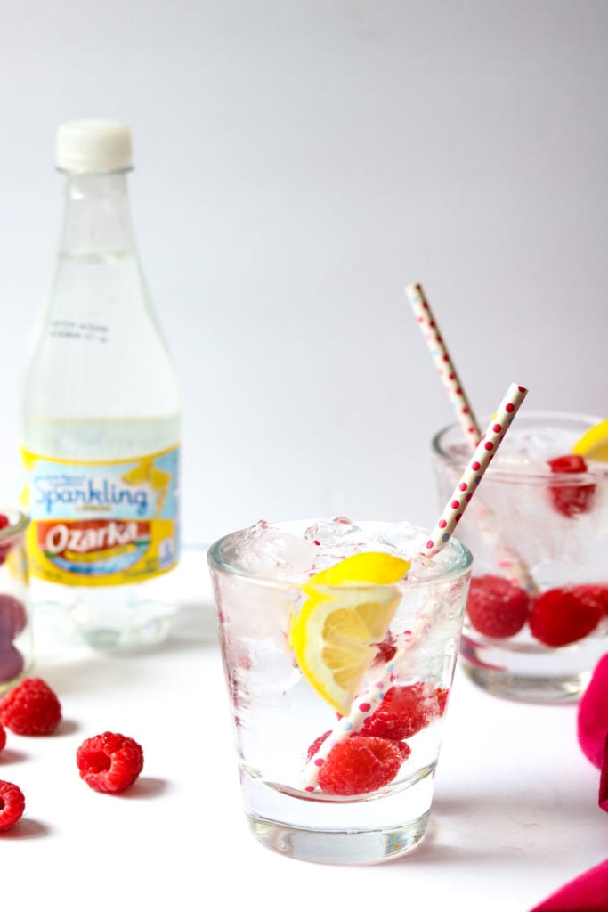 Raspberry vodka soda in glass garnished with fresh raspberries and lemon