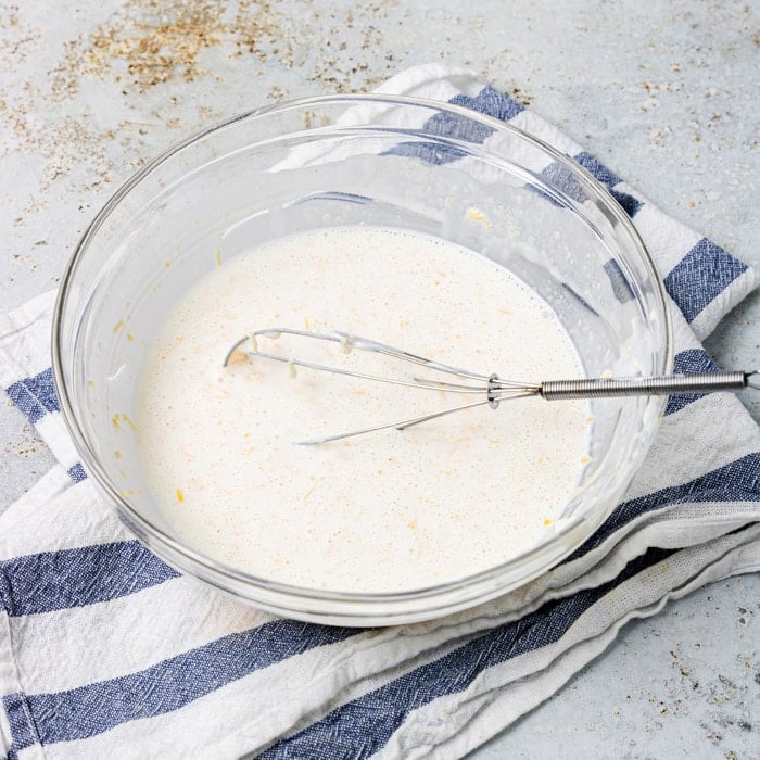 cheese sauce with a whisk in a glass bowl