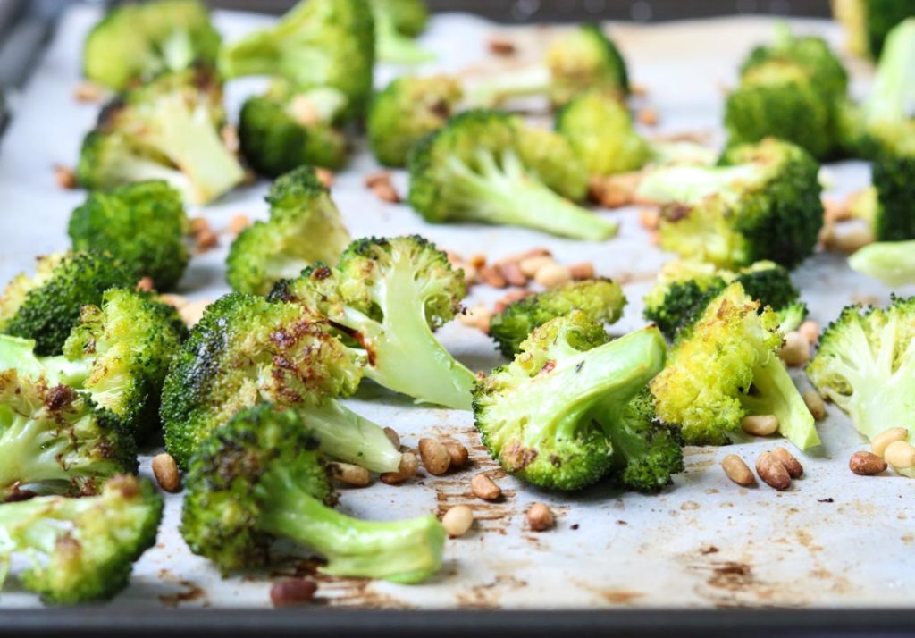 Oven Roasted Broccoli and pine nuts on a sheet pan lined with parchment paper