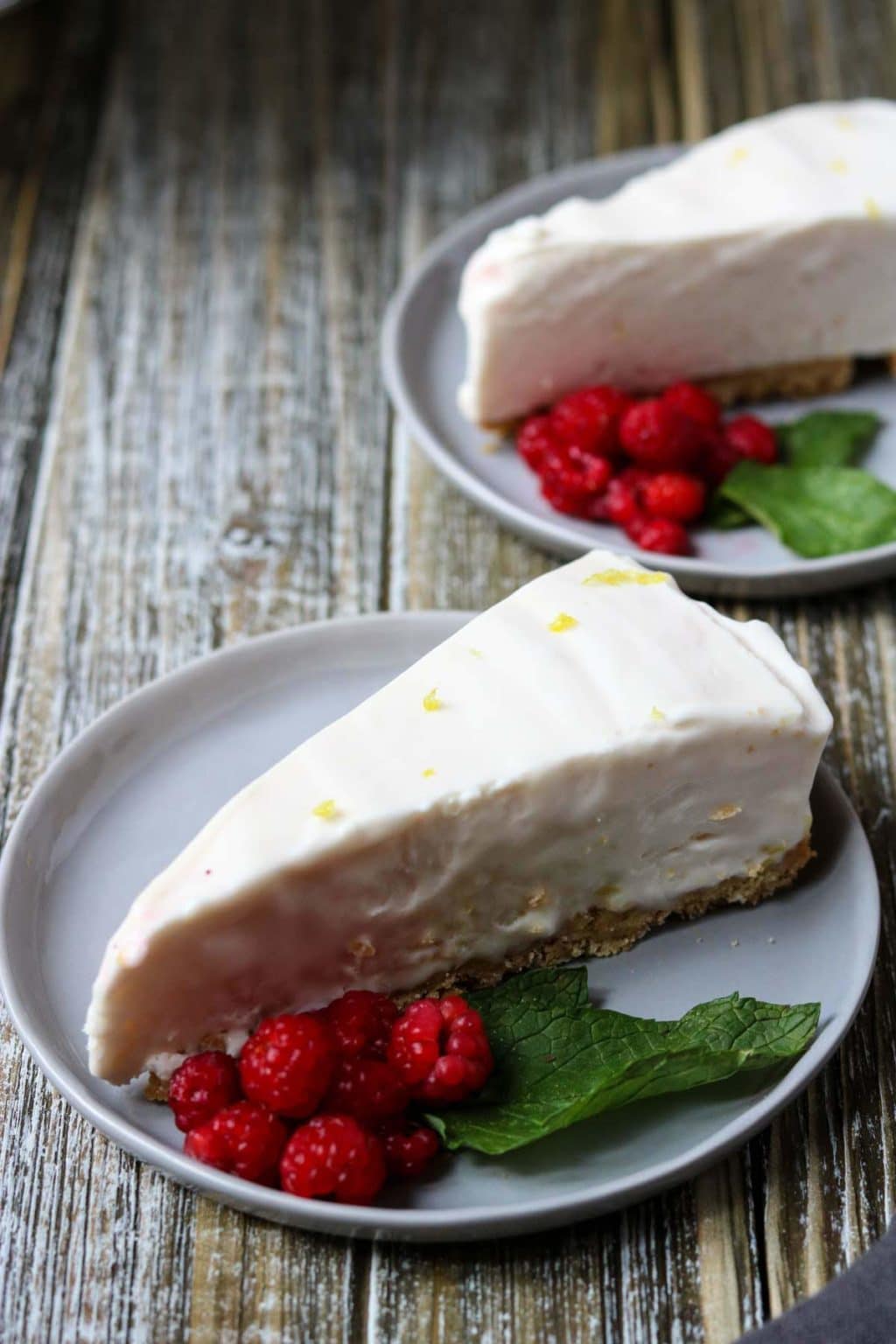 Two slices of Raspberry Lemonade Icebox Pie garnished with fresh raspberries and mint leaves