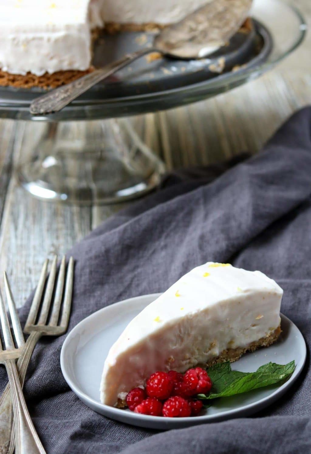 A slice of Raspberry Lemonade Icebox Pie garnished with fresh raspberries and mint leaves