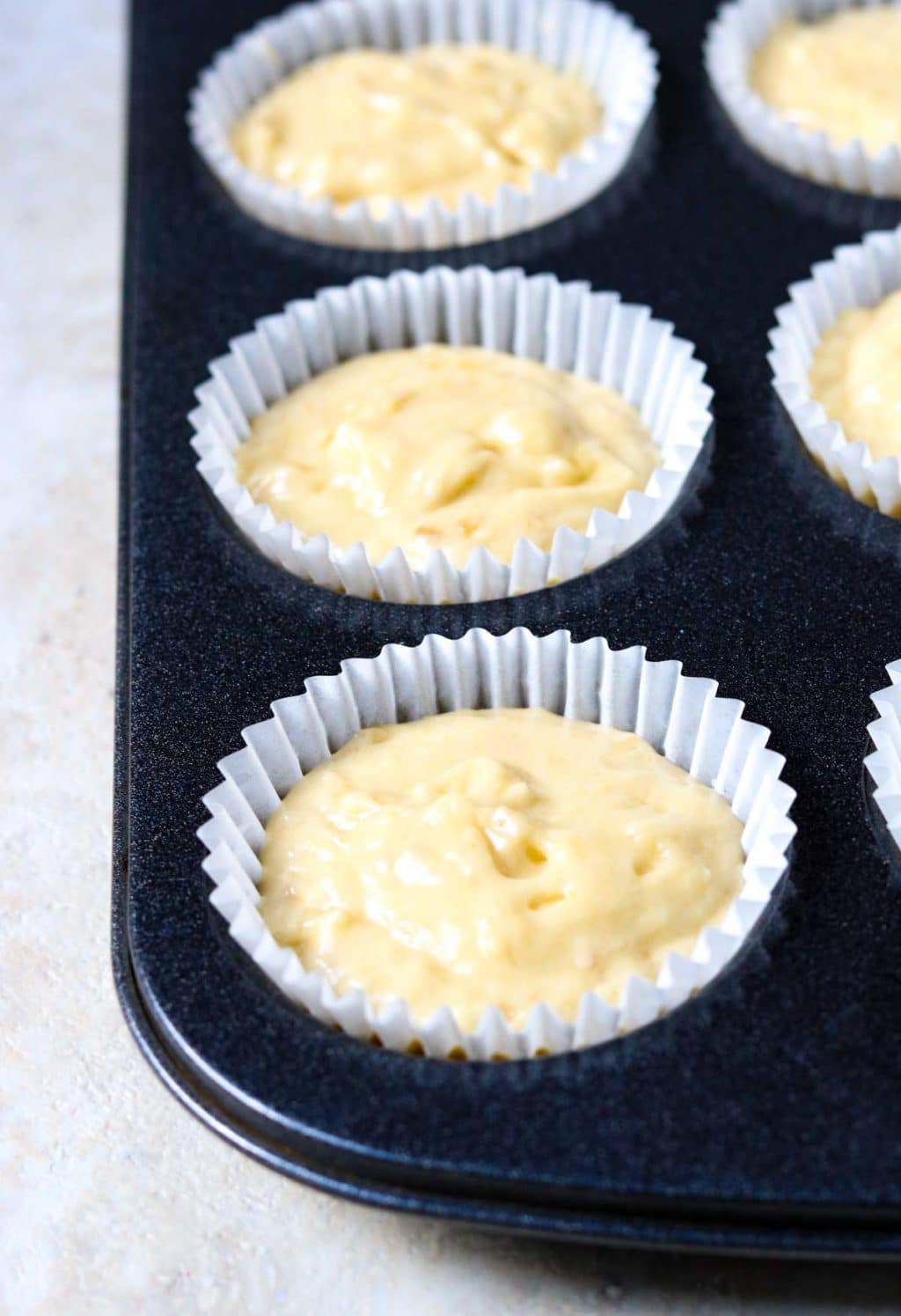 banana bread muffin batter in paper liners in a muffin tin