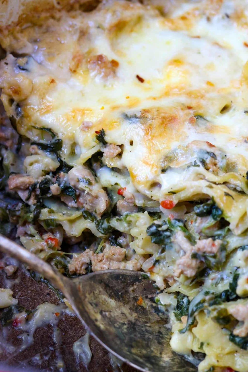 A scoop taken out of the Spinach Artichoke Lasagna to reveal the layers of ingredients