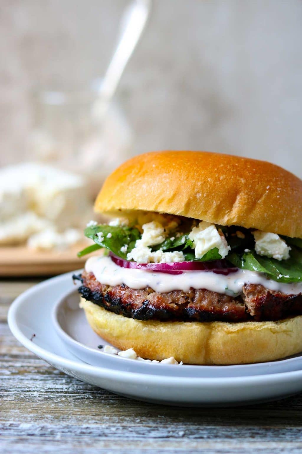 a turkey burger on a brioche bun with feta cheese and greek aioli