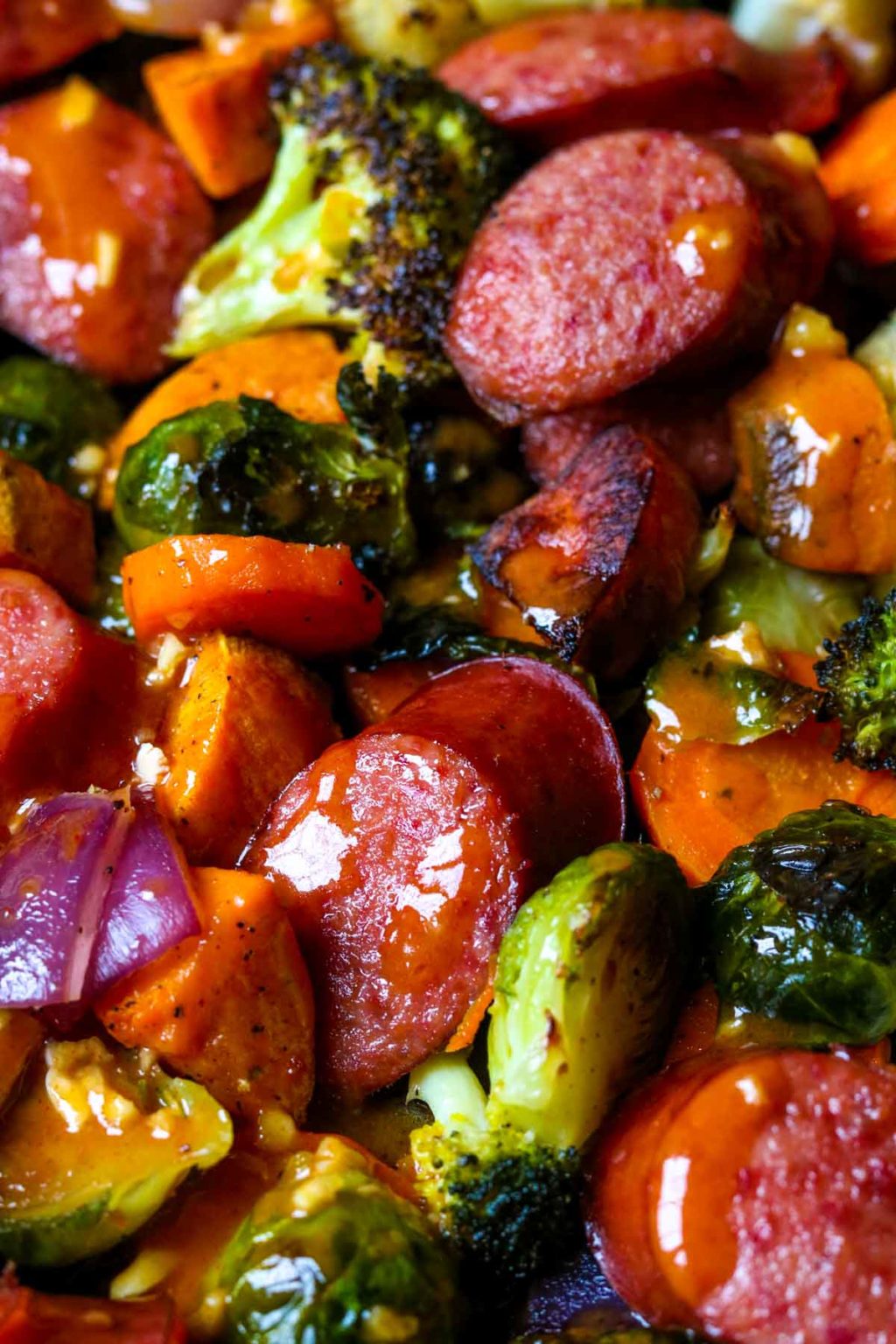 Close up picture of the smoked beef sausage, carrots, onions, brussel sprouts, broccoli, and sweet potatoes drizzles with smoked paprika vinaigrette