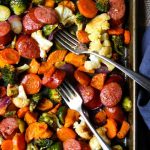 Healthy Sheet Pan Dinner with carrots, sweet potatoes, sausage, brussels, and drizzled with a smoked paprika vinaigrette