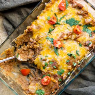 a baking dish full of refried beans topped with cheese, cilantro and tomatoes