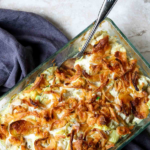 hot artichoke chicken salad in a glass baking dish topped with french fried onions, pinterest image