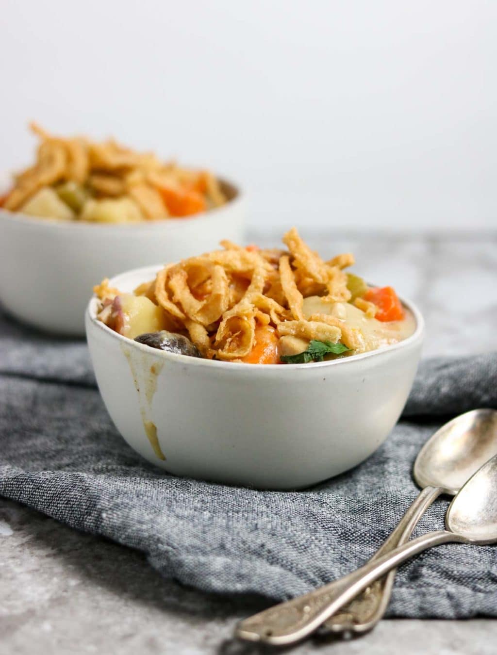 Chicken pot roast in a white bowl with spoons to the side