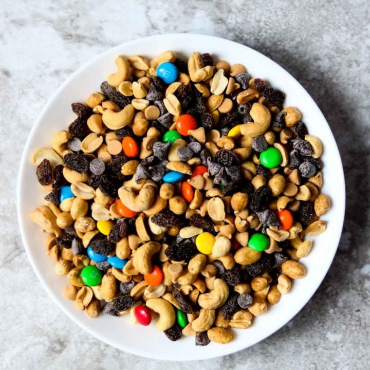 a white bowl full of trail mix that has M&M's in it
