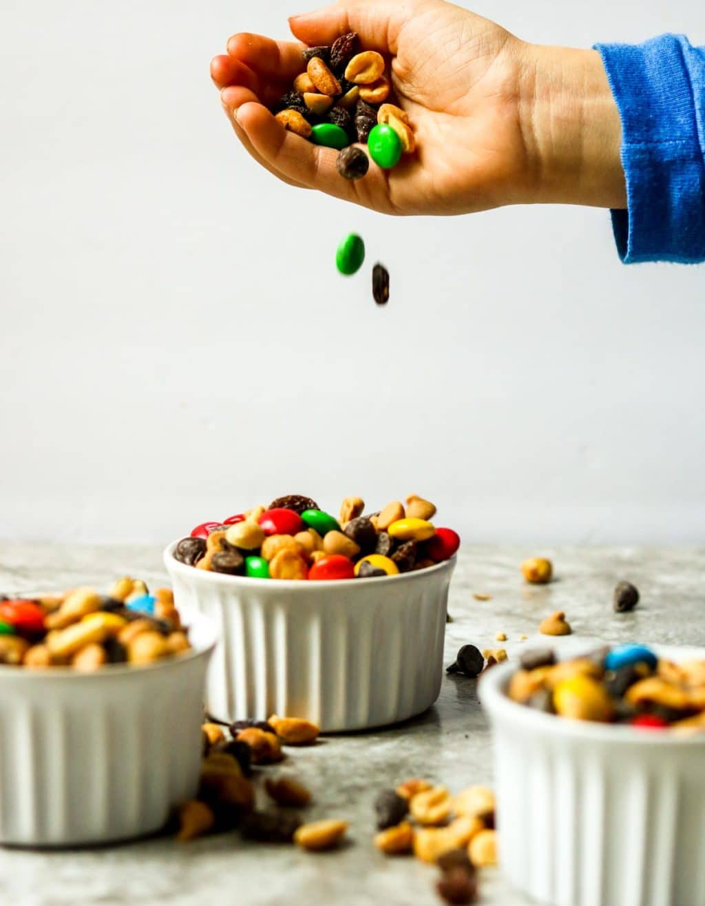 Monster Trail Mix spilling out of a hand into white bowls