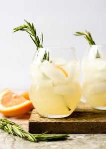 two glasses full of paloma cocktail garnished with rosemary
