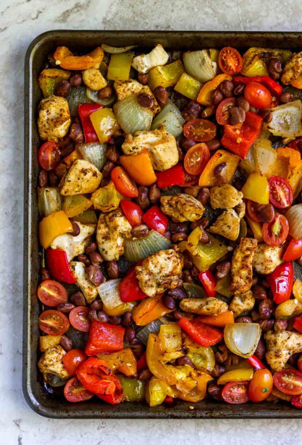 chicken and veggies seasoned with Mexican spices that have been cooked on a sheet pan