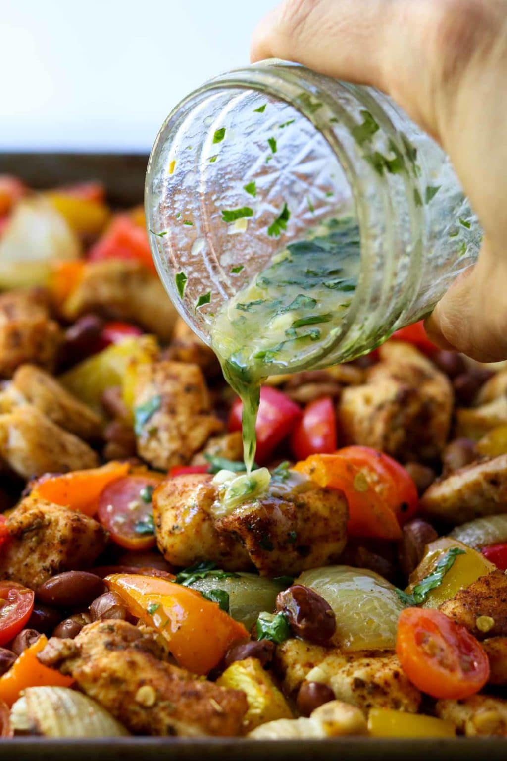 chicken fajita sheet pan dinner with cilantro lime vinaigrette being poured over the top