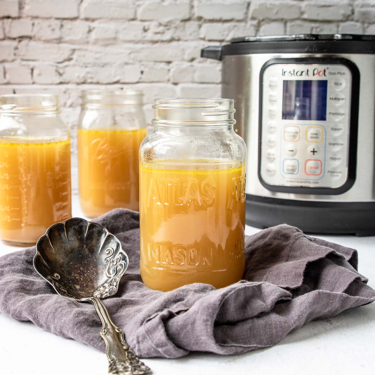 mason jars with chicken stock and an instant pot in the back