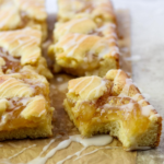 apple pie bars sliced into squares and drizzled with vanilla glaze